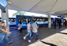 pessoas correndo em plataforma do ticen com ônbus estacionados em volta