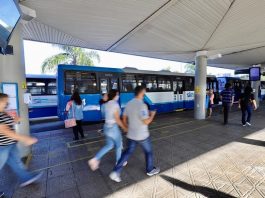 pessoas correndo em plataforma do ticen com ônbus estacionados em volta