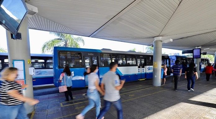 pessoas correndo em plataforma do ticen com ônbus estacionados em volta