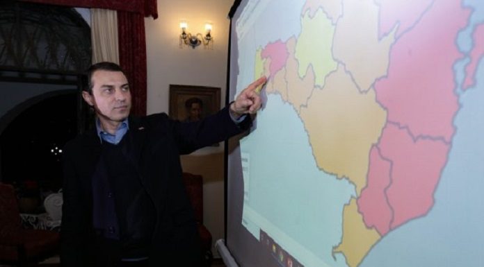 moisés aponta para um mapa de sc com escalas de cores por região de acordo com classificação de risco