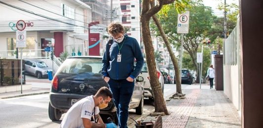 Posto de gasolina e centro comercial jogavam esgoto de banheiros na rede pluvial dois homens fiscalizando uma ligação de esgoto
