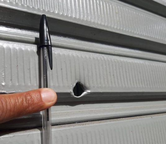 Tentativa de assalto em lotérica no Centro de Florianópolis tem tiroteio e duas prisões buraco de bala em porta de metal com uma caneta bic segurada ao lado para medir