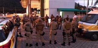 policiais reunidos em pé em roda ao lado de viaturas em posto policial
