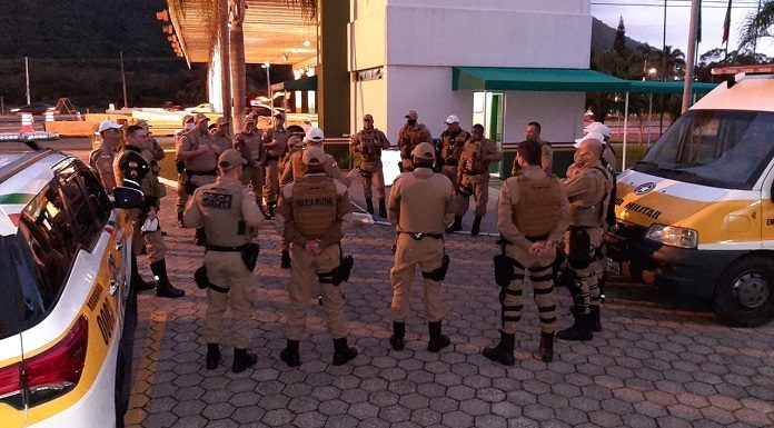 policiais reunidos em pé em roda ao lado de viaturas em posto policial