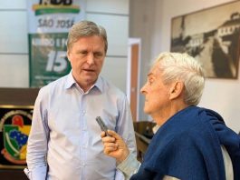 dário fala em gravador segurado por belmiro, ambos em pé no plenário da câmara de são josé