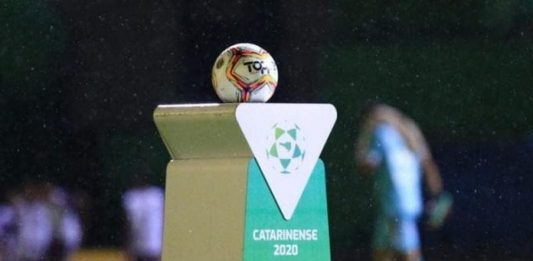 bola de futebol sobre uma bancada personalizada com logos do futebol catarinense 2020