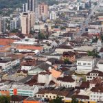 cidade de joinville com centenas de casas e prédios em área plana vista do alto