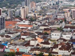 cidade de joinville com centenas de casas e prédios em área plana vista do alto