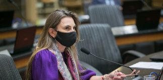 deputada paulinha usando máscara sentada em bancada do plenário da alesc