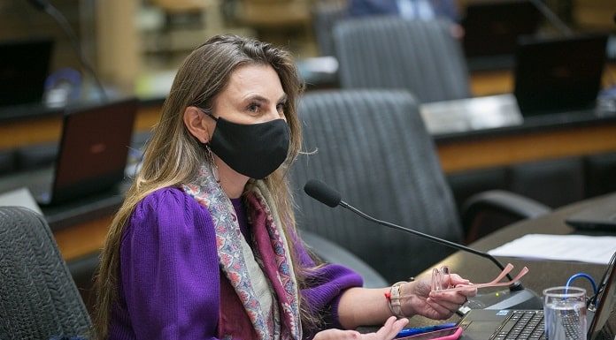 deputada paulinha usando máscara sentada em bancada do plenário da alesc