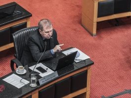 deputado maurício skulark visto de cima na bancada do plenário falando e gesticulando; há um notebook e papeis à sua frente