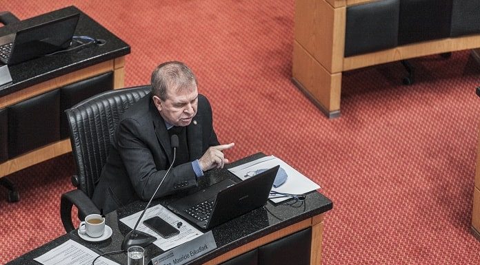 deputado maurício skulark visto de cima na bancada do plenário falando e gesticulando; há um notebook e papeis à sua frente