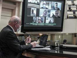 Prefeitos das maiores cidades participarão de audiência sobre a pandemia deputado marcos vieira usando máscara na tribuna da alesc e telão ao fundo com transmissão de outras pessoas