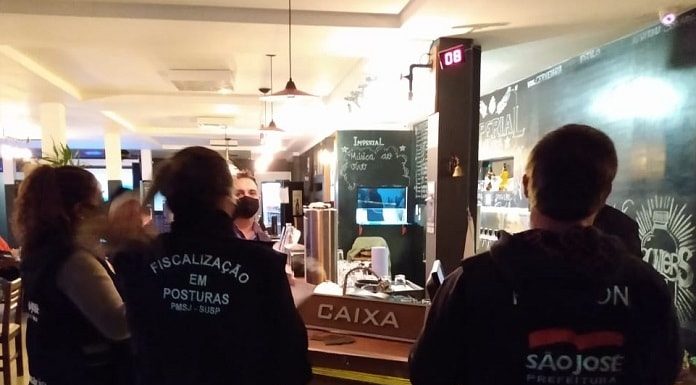 fiscais vistos usando colete em frente ao caixa de um bar de noite
