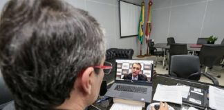 secretário de saúde visto de costas conversando pelo notebook com moisés