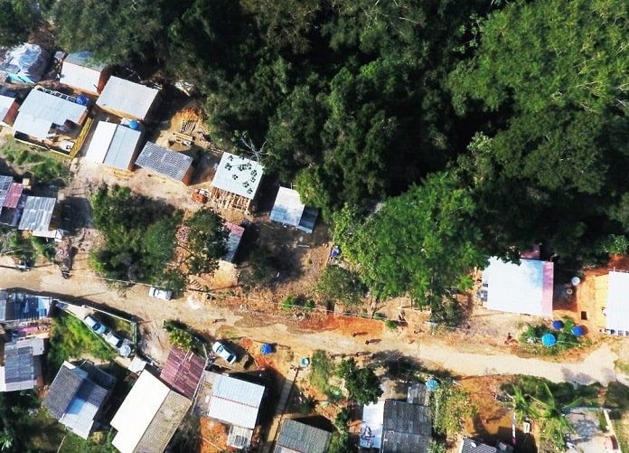 foto aérea de rua no meio das construções irregulares em área de mata