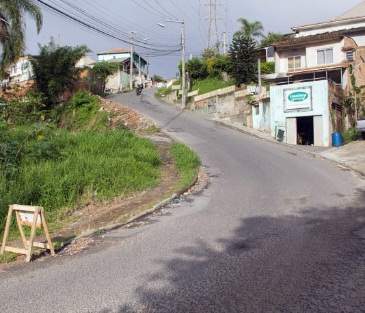 trecho em duas cuvas mais íngremes da rua com moto no alto e casas em volta