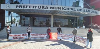 cinco pessoas seguram faixas uma em cada ponta em frente à prefeitura de são josé com mensagens de apoio ao isolamento social