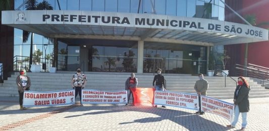 cinco pessoas seguram faixas uma em cada ponta em frente à prefeitura de são josé com mensagens de apoio ao isolamento social