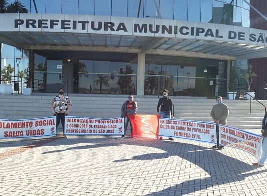 cinco pessoas seguram faixas uma em cada ponta em frente à prefeitura de são josé com mensagens de apoio ao isolamento social