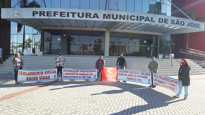 cinco pessoas seguram faixas uma em cada ponta em frente à prefeitura de são josé com mensagens de apoio ao isolamento social