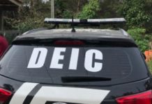 Carro preto com adesivo da DEIC no vidro traseiro