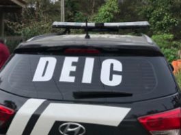 Carro preto com adesivo da DEIC no vidro traseiro
