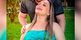 foto de book de gestante de flávia onde aparece grávida, de olhos, fechados, sorridente e sendo abraçada e beijada pelo marido