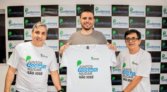 Marcondes, Costa e Natal posam para foto uniformizados com camisa do partido e sorridentes. Painel de logos do partido ao fundo