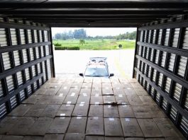 250 mil maços de cigarros contrabandeados são apreendidos na BR-101 foto de dentro do baú do caminhão sobre todas as caixas de cigarros gift organizadas; ao fundo baú aberto e viatura lá fora