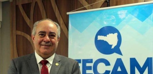 Após prisão, Orildo Severgnini renúncia à presidência da Fecam orildo sorridente para a foto ao lao de banner da fecam