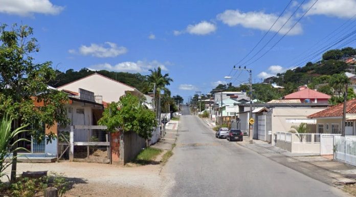 rua de forquilhas ao longo da imagem com diversas residência ao longo. dois carros estacionados