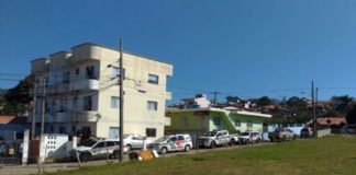 viaturas da pm estacionadas em servidão ao lado de grande terreno baldio em frente ao pequeno prédio de três andares