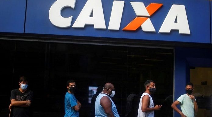 homens em fila usando mascara em frente a agencia da caixa