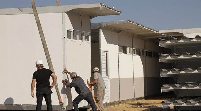 homens montando uma estrutura modular para a escola