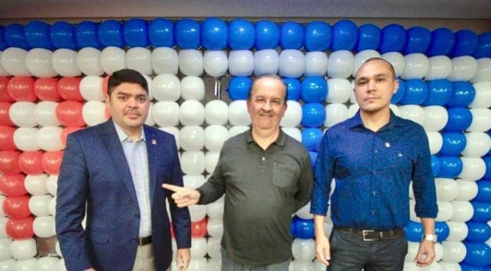 clonny, jorginho e galeno posam para foto em frente a mural de balões; jorginho aponta para clonny sorridente