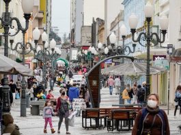 algumas mulheres de máscara andando no calçadão da felipe schimidt no centro de florianópolis; viatura ao fundo