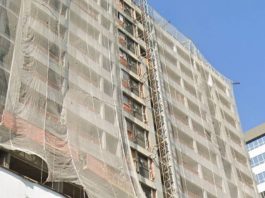 bloco de apartamentos em construção visto de baixo com grande tela protetora; cerca de 12 andares