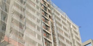 bloco de apartamentos em construção visto de baixo com grande tela protetora; cerca de 12 andares