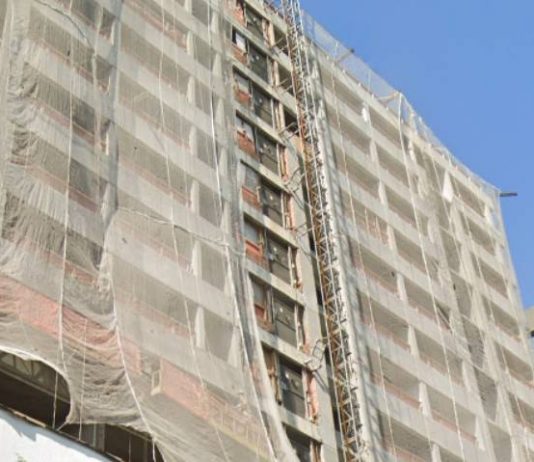 bloco de apartamentos em construção visto de baixo com grande tela protetora; cerca de 12 andares