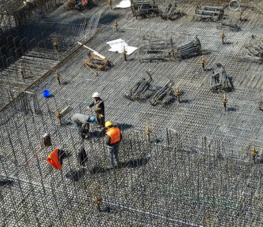operários em grande local com piso de barras de ferro para ser concretado