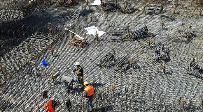 operários em grande local com piso de barras de ferro para ser concretado