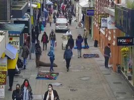 SC tem 8,4% de desocupação e 20,1% de pessoas trabalhando na informalidade pessoas usando máscaras e roubas de frio andam no calçadão de rua no centro de florianópolis; carro da polícia; comércio em volta