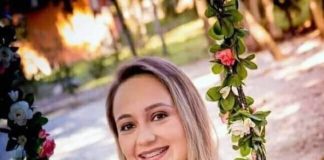 flavia godinho mafra em foto grávida sentada em balanço com flores segura um sapatinho de bebê sobre a barriga