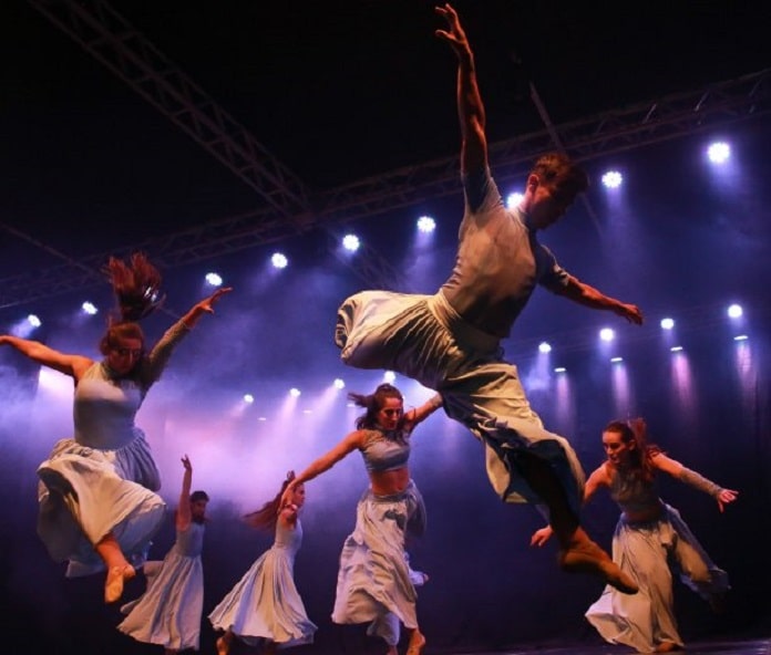 homens e mulheres apresentando uma dança em um palco