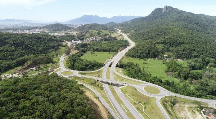foto aérea do contorno viário onde há rotatórias e morro da pedra branca ao fundo