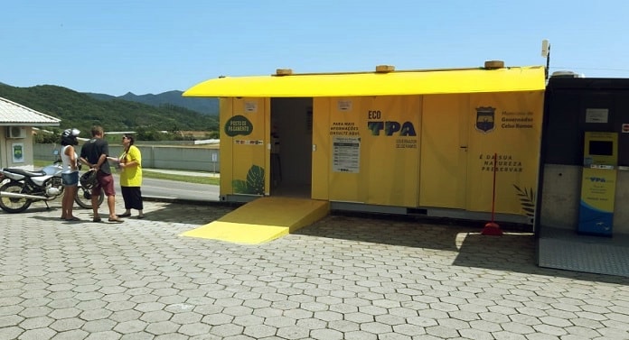 posto de cobrança da tpa em estacionamento; funcionária fala com casal ao lado de moto