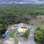 foto aérea de estação de tratamento de esgoto ao lado de grande área de mata