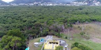 foto aérea de estação de tratamento de esgoto ao lado de grande área de mata