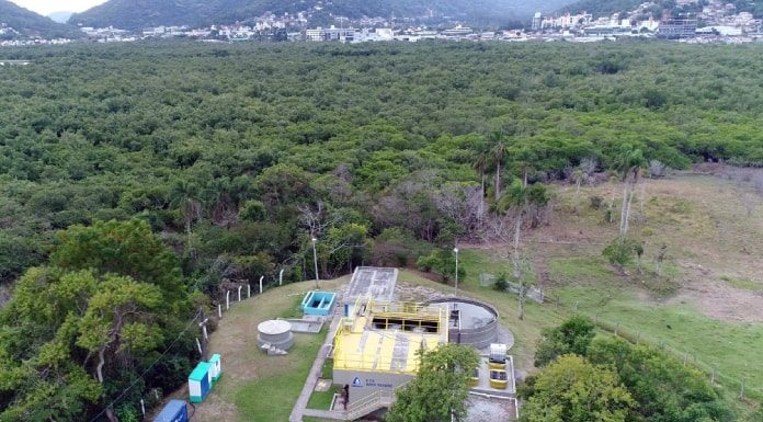 foto aérea de estação de tratamento de esgoto ao lado de grande área de mata